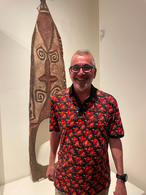 Xavier wearing the Bird of Paradise polo in Barcelona alongside a PNG artifact